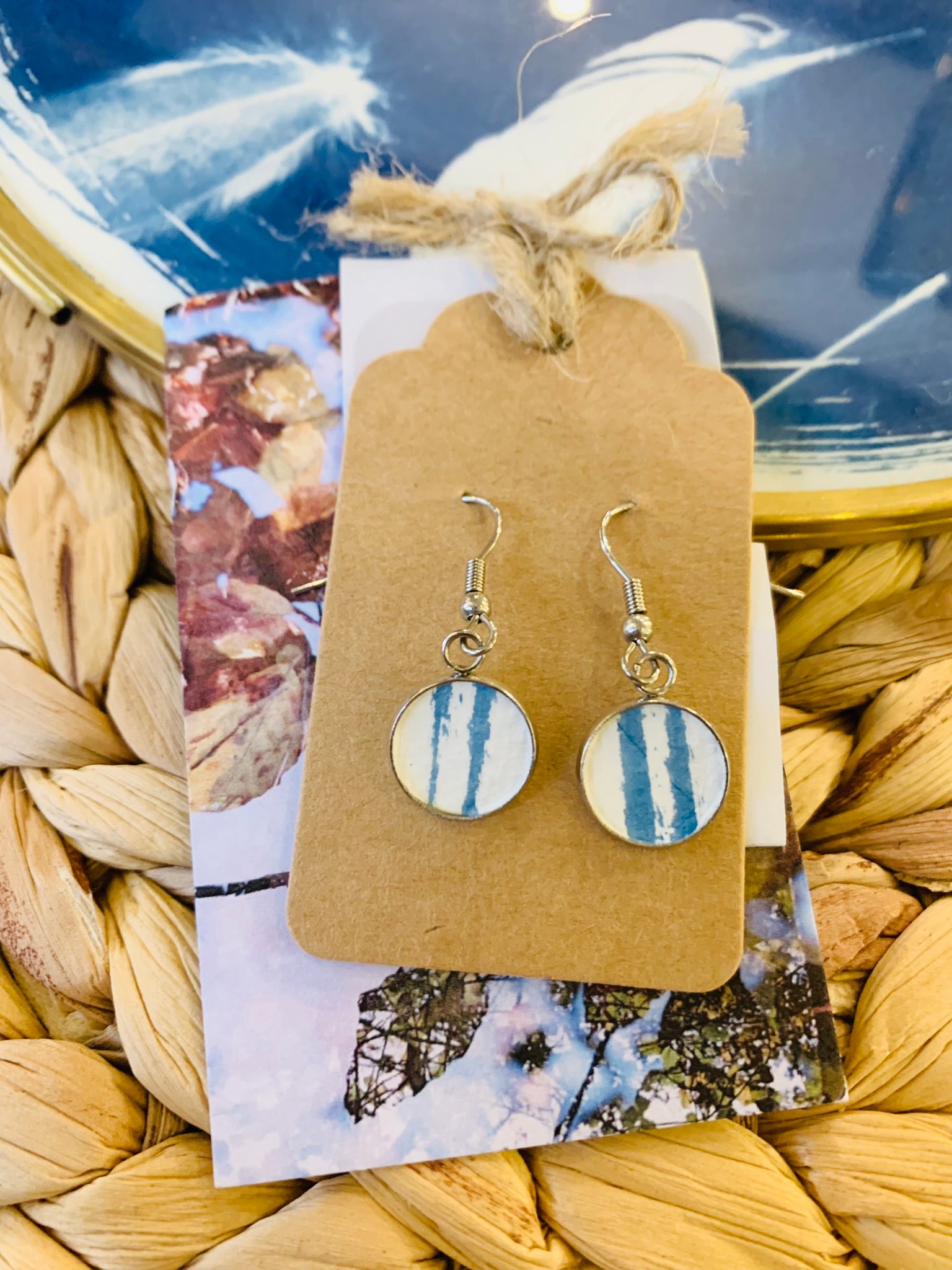 double thin brushstroke line of original print in tray of pair of dangly stainless steel earrings